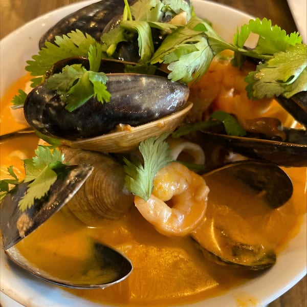 Colombian seafood cazuela with mussels, clams, shrimp, and cilantro in a rich orange broth.