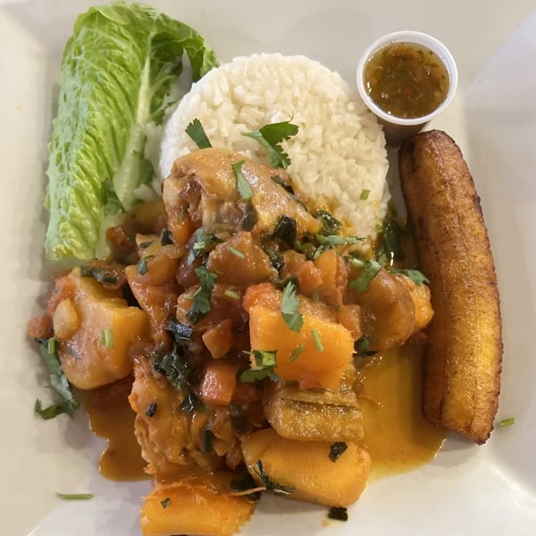 Colombian chicken stew with potatoes, rice, lettuce, fried plantain, and a side of ají.